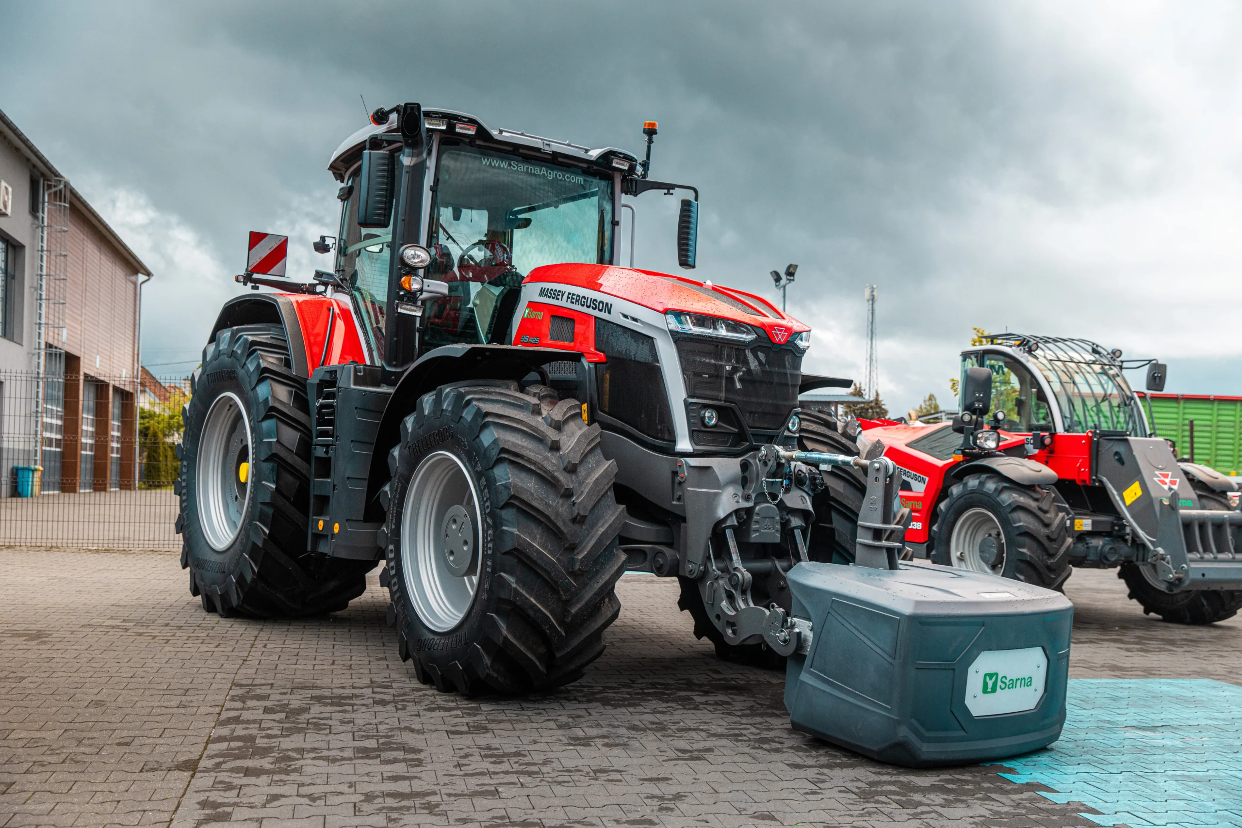 Czerwony ciągnik Massey Ferguson 9S.425 z obciążnikiem na placu pokazowym.